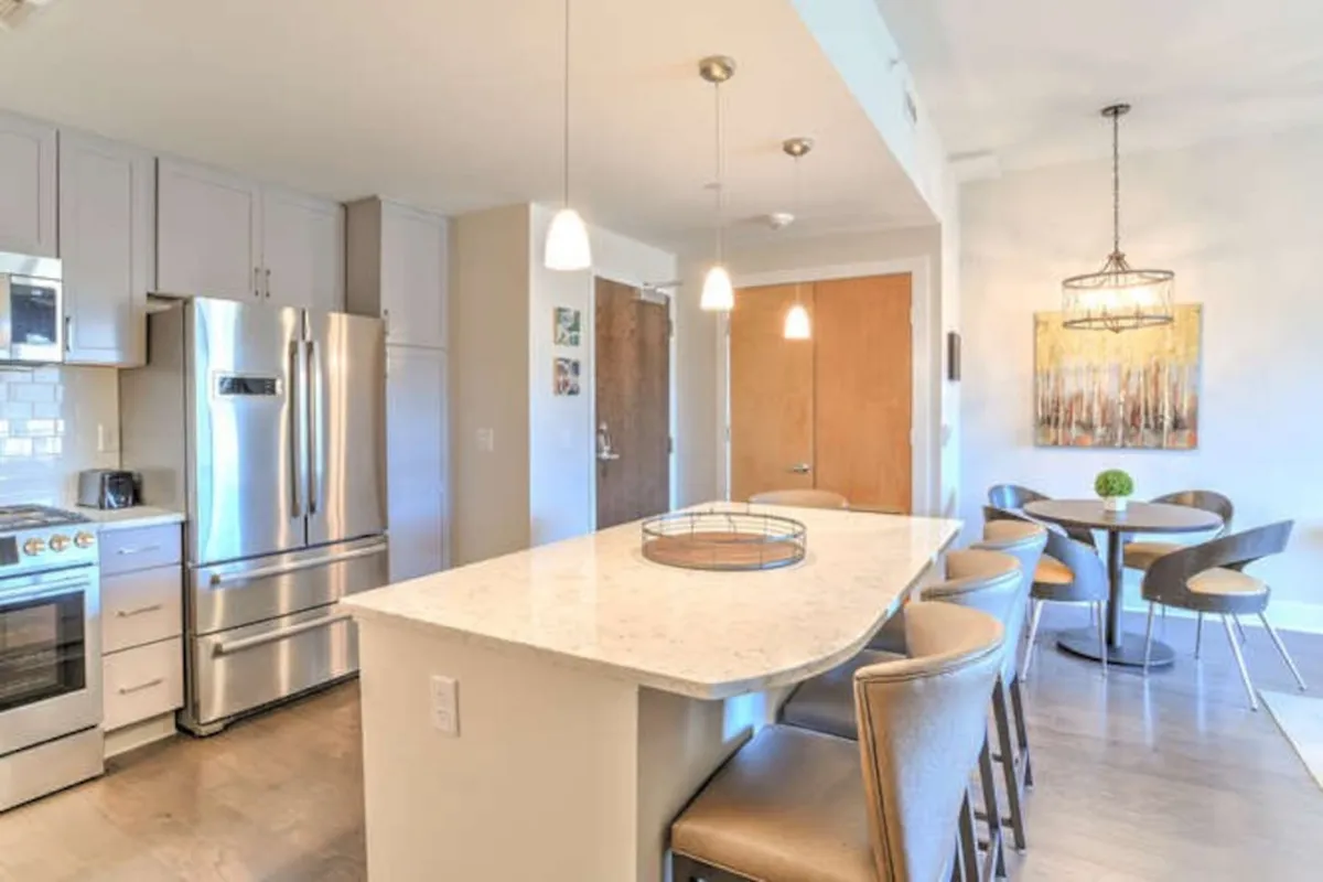 The image highlights a welcoming kitchen and dining space, featuring a central island, stainless steel appliances, and a generously sized dining table. The setup is ideal for both cooking and communal feasts, providing enough room for group seating and shared meals.